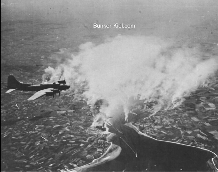 Datei:01 Das Foto zeigt Kiel und die Kieler Förde von Norden gesehen bei einem amerikanischen Luftangriff. Das gesamte Gebiet ist eingehüllt in weiß.jpg